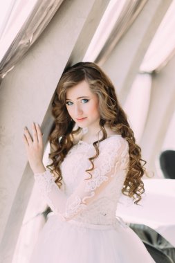 Beyaz elbiseli büyüleyici gelin ve kafede pencereyakınında poz kıvırcık saç modeli ile, yakın çekim