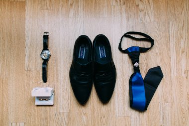 Erkek aksesuarları: ayakkabı, saat, gözlük, ahşap arka plan üzerinde kravat.