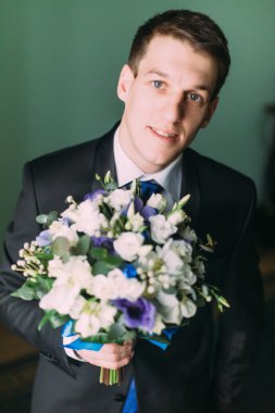 Bir düğün buketi yakın çekim ile siyah takım elbise yakışıklı zarif damat