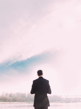 Young man in black suit against the sky
