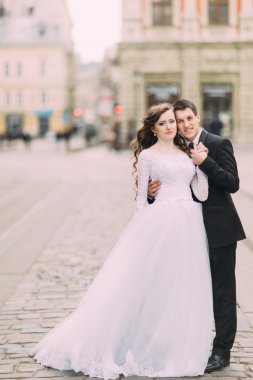 Siyah elbiseli yakışıklı damat gelin beyaz elbise, eski güneşli şehir arka plan var el tutar