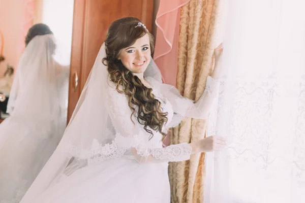 Boldog menyasszony, menyasszonyi ruha és a fátyol-napos ablak közelében — Stock Fotó