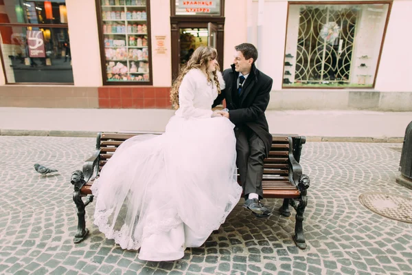 Casal romântico de noiva e noivo sentado no banco de madeira na rua da cidade velha — Fotografia de Stock