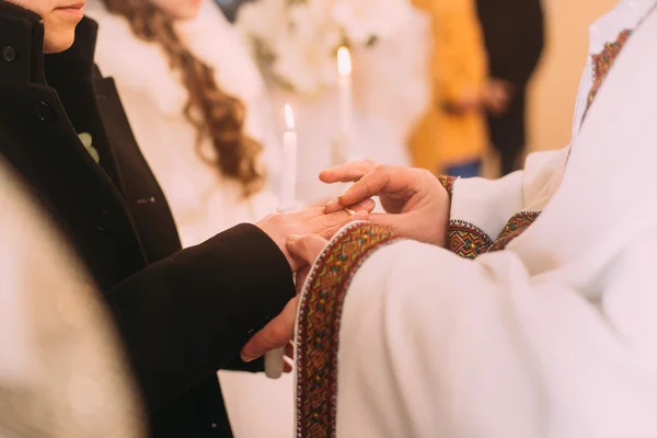 O sacerdote veste um anel no dedo para noivo durante o casamento da igreja — Fotografia de Stock