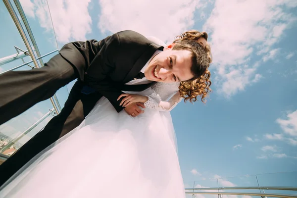 下から見る青い空の雲に対してカメラのためにポーズ新郎新婦の笑みを浮かべて、 — ストック写真