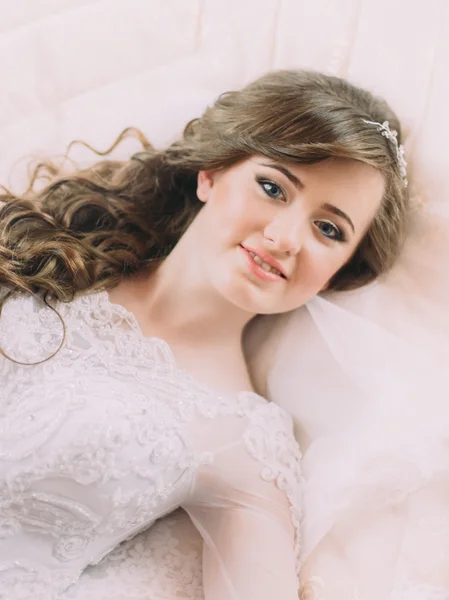 Portret van mooie bruid in witte jurk en sluier op bed in trouwdag — Stockfoto