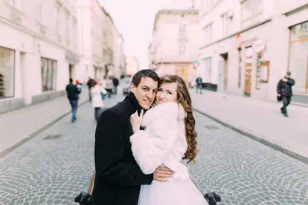 Beautiful married couple standing embracing in the old city with wonderful architecture — Stock Fotó