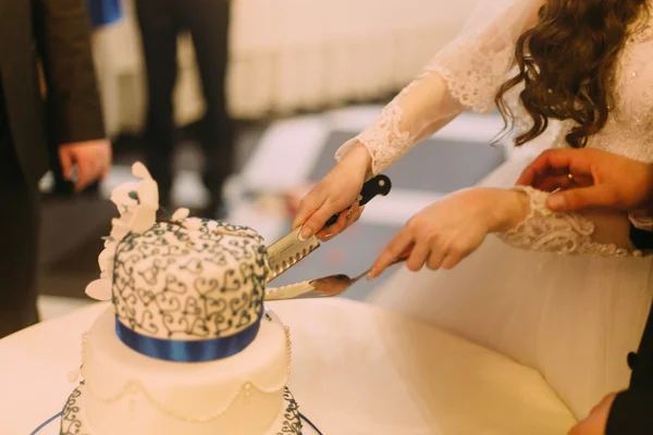 Beauté mariée et beau marié coupent gâteau de mariage blanc décoré avec ruban bleu — Photo