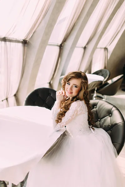 顔の近くに手をつないでカフェに座っている長い巻き毛を持つ美しい花嫁 — ストック写真