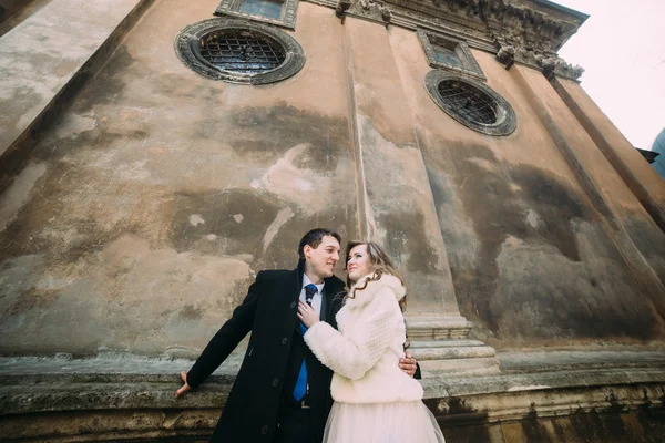 Lächelndes romantisches Brautpaar, das sich vor der alten Burgmauer umarmt, Nahaufnahme von unten — Stockfoto