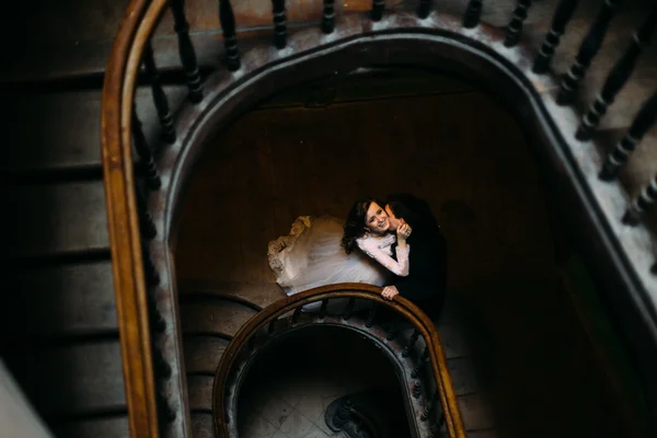 Przystojny oczyszczenie Całowanie piękny uśmiechnięta Panna Młoda na starych drewnianych schodach w pomieszczeniu, widok z góry — Zdjęcie stockowe