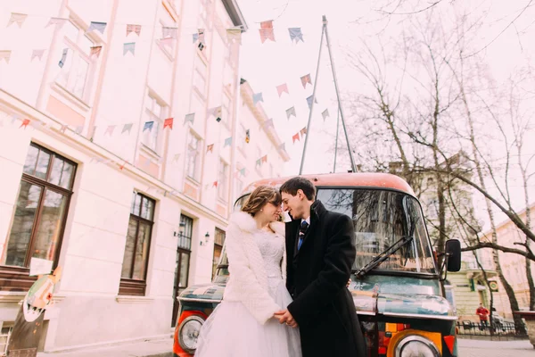 Casamento feliz casal empracing comovente testa perto colorido retro carro — Fotografia de Stock