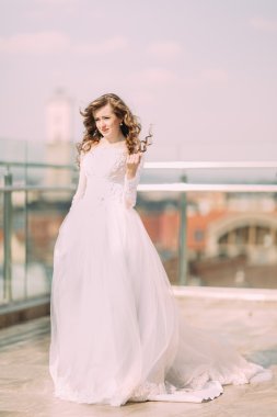 Terasta poz gelinlikle uzun kıvırcık saçlı güzel gelin