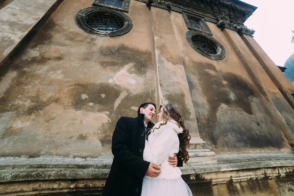 Sorrindo casal recém-casado romântico abraçando na frente da parede do castelo velho, close-up vista de baixo — Fotografia de Stock