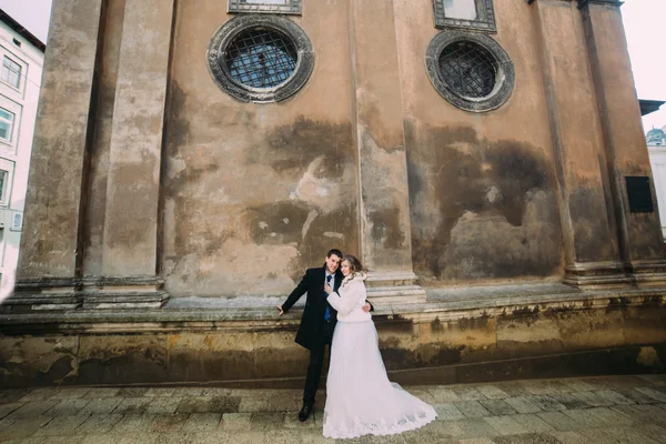 Sorrindo casal recém-casado romântico abraçando na frente da antiga parede do castelo — Fotografia de Stock