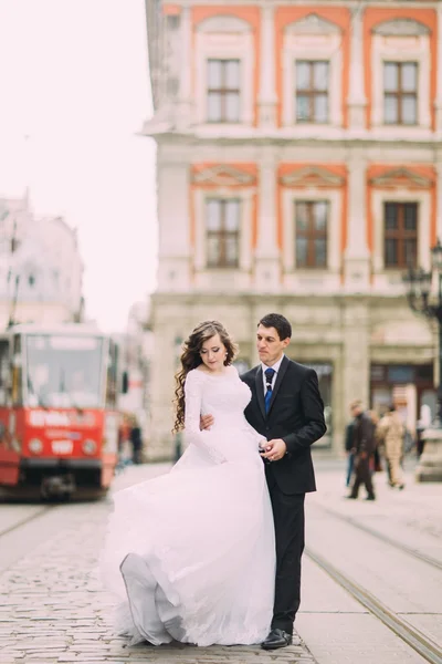 Felice sposo e sposa passeggiando per le strade della città vecchia con tram sullo sfondo — Foto Stock