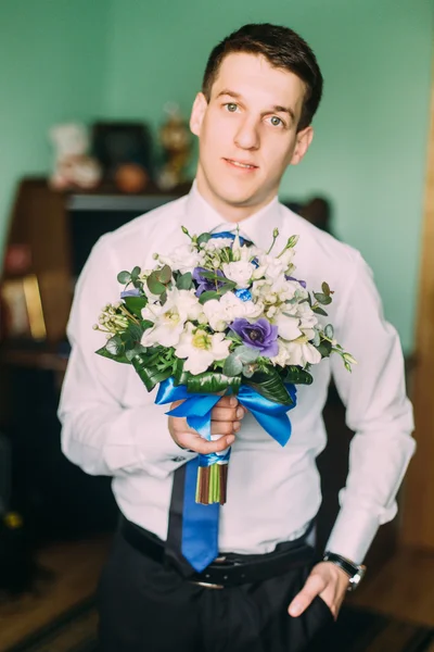 Beau homme d'affaires tenant des fleurs et regardant la caméra à l'intérieur — Photo