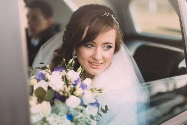Atractiva novia caucásica en coche de bodas sonriendo mirando a través de la ventana — Foto de Stock