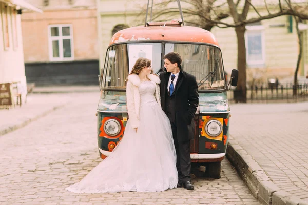 Feliz casal empracing perto de carro retro colorido — Fotografia de Stock