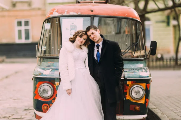 Feliz pareja casada practicando tocar frentes cerca de colorido coche retro —  Fotos de Stock