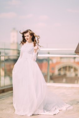 Terasta poz gelinlikle uzun kıvırcık saçlı güzel gelin