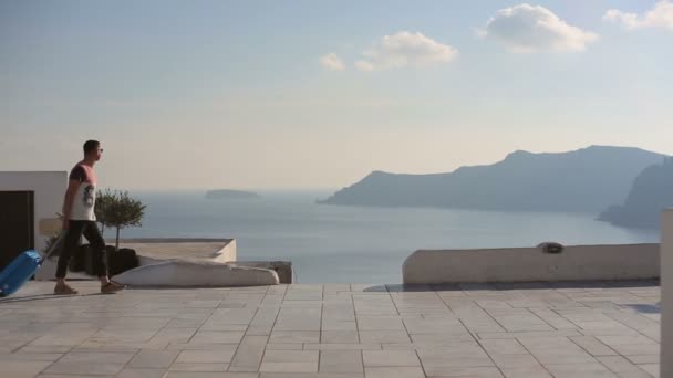 Šťastný muž turista se zavazadly v Santorini si svou letní dovolenou — Stock video