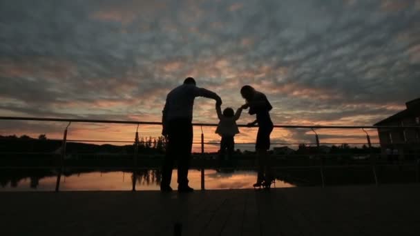 Silhouettes of happy family walking together at sunset — Stock Video