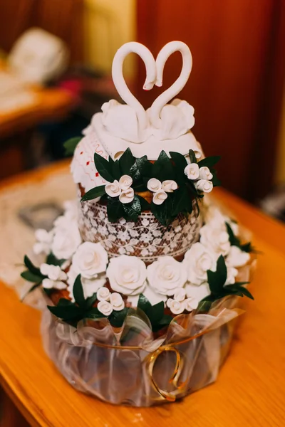 Carino torta nuziale con foglie verdi, rose bianche e due cigni in cima — Foto Stock