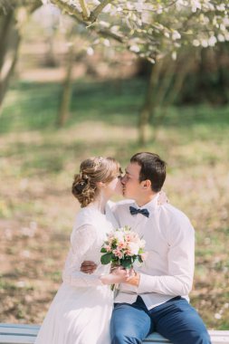 Birbirimizi düğün çiçek buketi elinde açık havada tutan öpüşme genç yeni evli çift