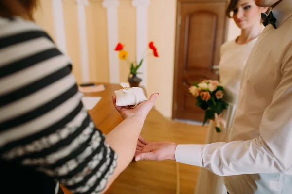 Szczęśliwa panna młoda i pan młody biorąc biały poduszkę witn pierścieni podczas rejestracji ślubu — Zdjęcie stockowe