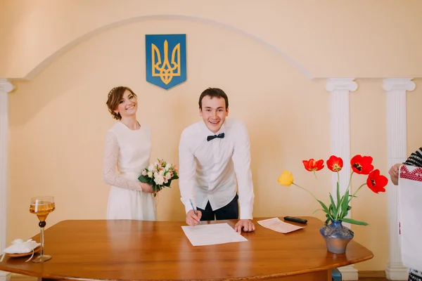 Bello sposo sorridente che firma il certificato di matrimonio alla cerimonia nell'ufficio del registro — Foto Stock