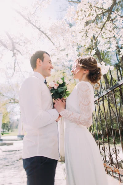 Молода наречена і наречена обіймаються букетом весняних квітів біля паркану — стокове фото