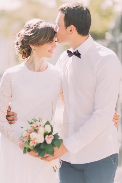 Noivo amoroso beijar noivas testa no passeio de casamento . — Fotografia de Stock