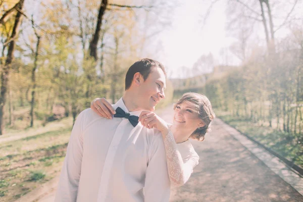 Felice sposa in piedi dietro fissaggio papillon blu del suo sposo sorridente in camicia bianca — Foto Stock