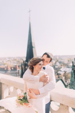 Eski şehir manzarası ile balkonda sarılma güzel düğün çift, yakın çekim