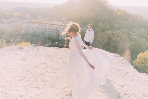 Молодой жених в белой рубашке и лук, стоящий позади танцующей красивой невесты в свадебном платье — стоковое фото