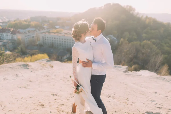美しい若いカップルは、自然と都市の背景で丘の上にキス. — ストック写真