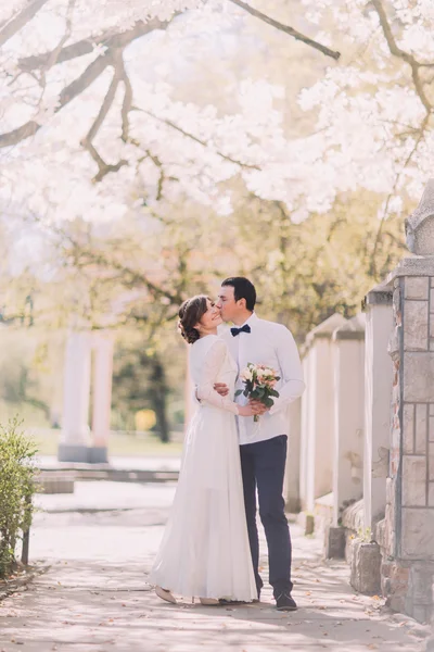 Braut und Bräutigam am Hochzeitstag umarmen sich im Freien an der Frühlingsnatur. — Stockfoto