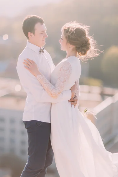 Primo piano di una romantica coppia di sposi che si guardano e si abbracciano con le braccia sullo sfondo della città — Foto Stock