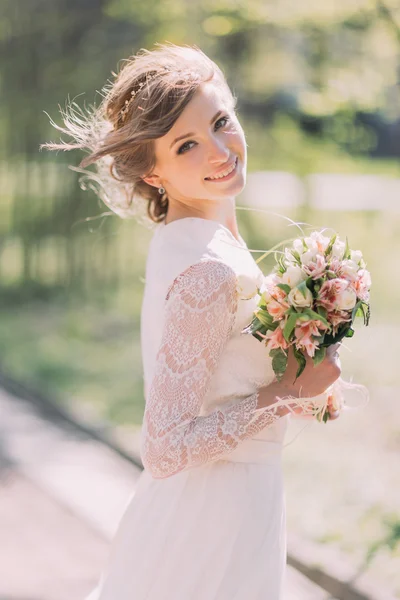 Närbild porträtt av magiska vackra unga bruden bär elegant vit klänning med bukett i parken. — Stockfoto