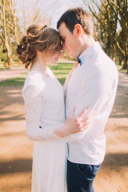 Genç gelin ve damat bahar parkında alınlarına dokunuyor.