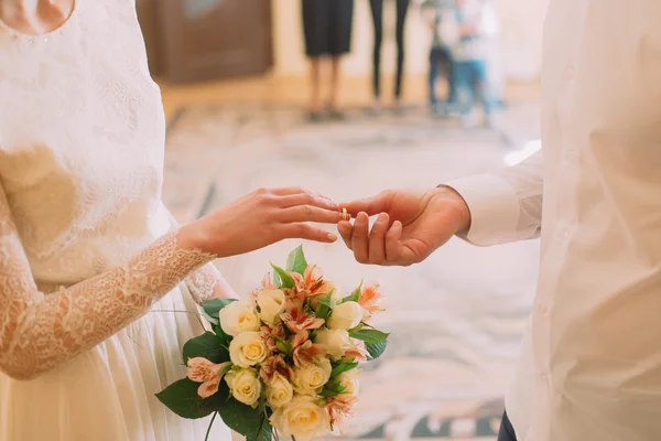 Bonito noivo na camisa branca colocando anel de casamento na noiva elegante no registro, close-up — Fotografia de Stock