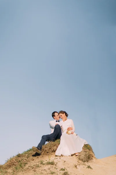 Νέοι ευτυχισμένη απλά παντρεμένο ζευγάρι που κάθεται στην κορυφή του βουνού. Την ημέρα του γάμου — Φωτογραφία Αρχείου