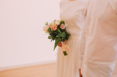 Gelin damat yakın ayakta turuncu ve beyaz çiçekler güzel bir buket tutar