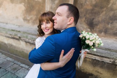 Mutlu evli çift birlikte eski kahverengi duvarının yakınında geleceğe doğru seyir kilise, yakın çekim