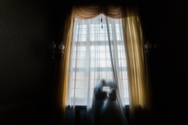 Gelin ve damat öpüşme perdeler ile cama silüeti