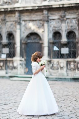 Genç gülümseyen gelin gül buketi cityscape ile arka plan üzerinde seyir.