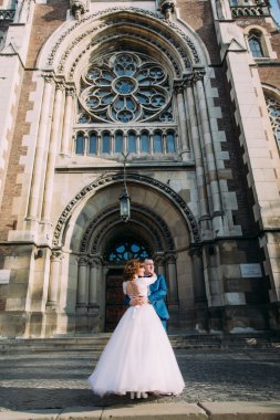 mutlu muhteşem gelin ve kentin muhteşem bir bina Kilisesi'nin arka plan üzerinde şık yakışıklı damat