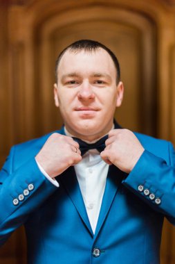 Gülümseyen yakışıklı zengin ahşap iç onun papyon ekstralarıyla mavi elbiseli