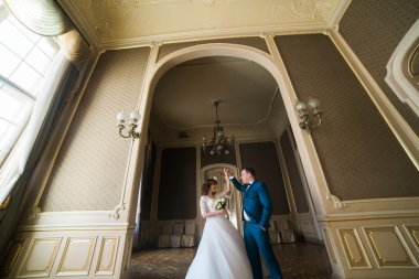 Güzel gelin buketi ve yakışıklı damat arch sarı duvarlar arka plan adlı dans Mavi takım elbise ile